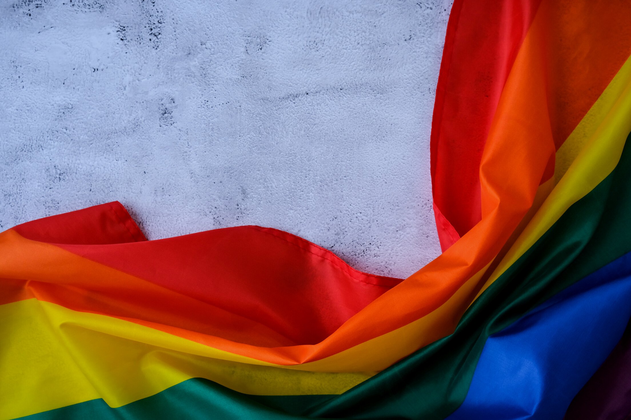 Rainbow Flag on Concrete Background with Copy Space. Rainbow Lgbtq Flag Made from Silk Material. Symbol of LGBTQ Pride Month. Equal Rights. Peace and Freedom